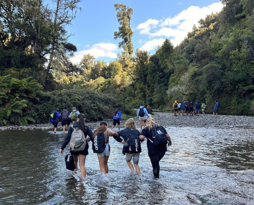 Eine Gruppe Trident High School Schüler durchquert einen flachen Fluss