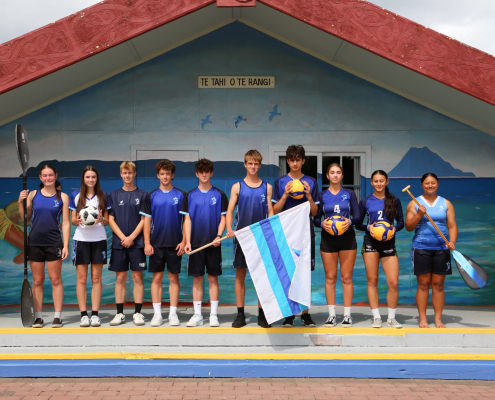 Trident High School Schüler präsentieren verschiedene Sportarten vor einem traditionellen Maori Gebäude